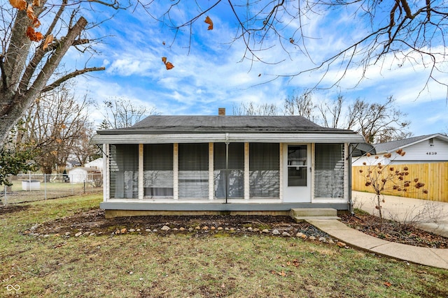 back of house with a sunroom and a lawn