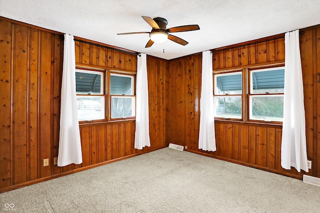 carpeted empty room featuring ceiling fan and a textured ceiling