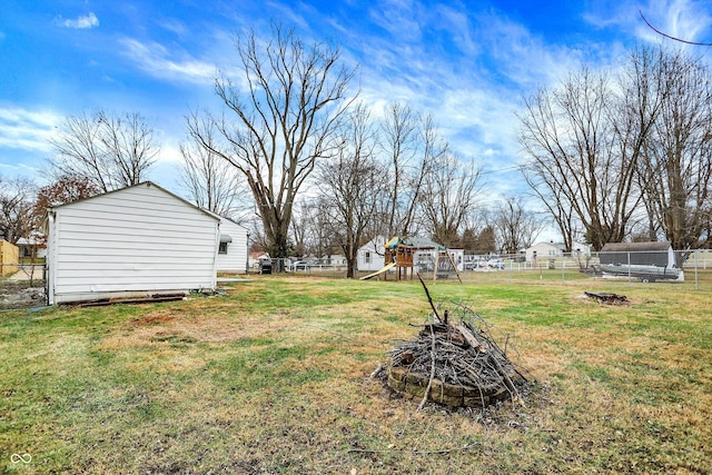 view of yard featuring a playground, a fire pit, and a trampoline