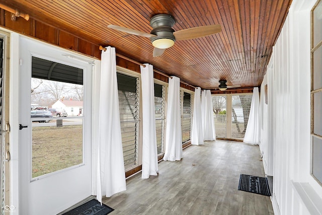 unfurnished sunroom featuring ceiling fan, a healthy amount of sunlight, and wood ceiling