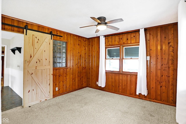 unfurnished bedroom featuring light carpet, ceiling fan, and wood walls