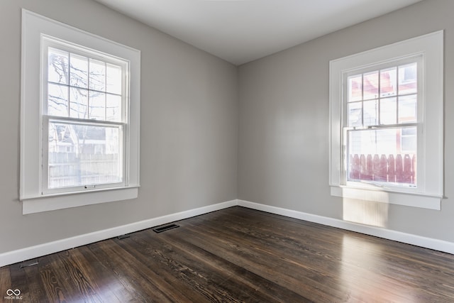 empty room with dark wood-type flooring and a healthy amount of sunlight