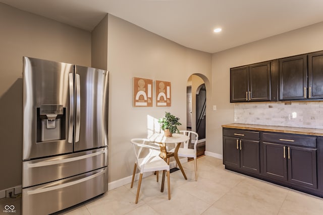 kitchen with light tile patterned floors, backsplash, dark brown cabinets, and stainless steel fridge with ice dispenser