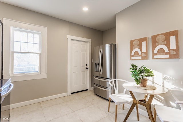 kitchen featuring electric stove, light tile patterned floors, and stainless steel fridge with ice dispenser