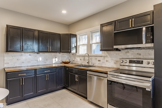 kitchen with decorative backsplash, sink, stainless steel appliances, and wood counters