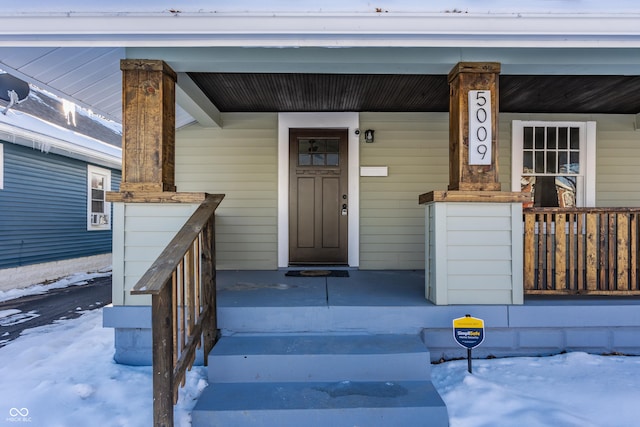 snow covered property entrance featuring a porch