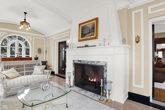 living room featuring a premium fireplace, crown molding, vaulted ceiling, and an inviting chandelier