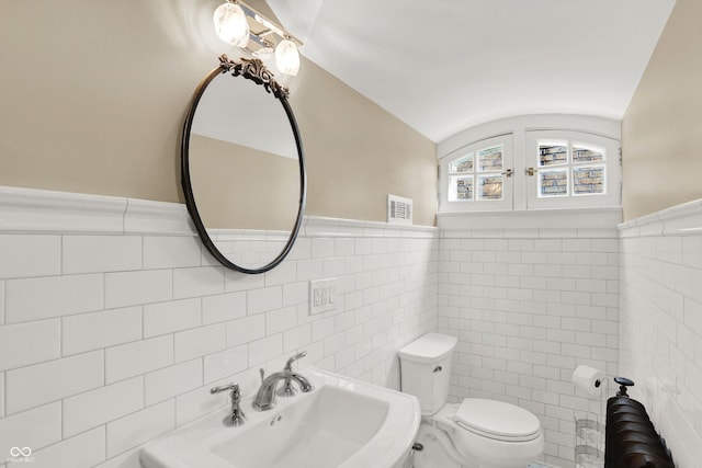 bathroom with lofted ceiling, sink, and tile walls