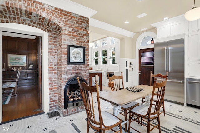 dining space featuring a brick fireplace and ornamental molding