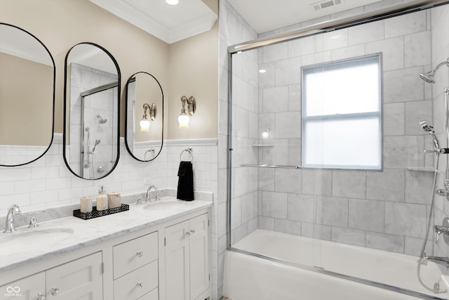 bathroom featuring vanity, ornamental molding, tile walls, and combined bath / shower with glass door