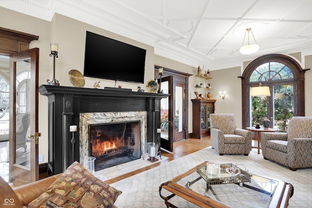 living room featuring a high end fireplace, light hardwood / wood-style floors, and coffered ceiling