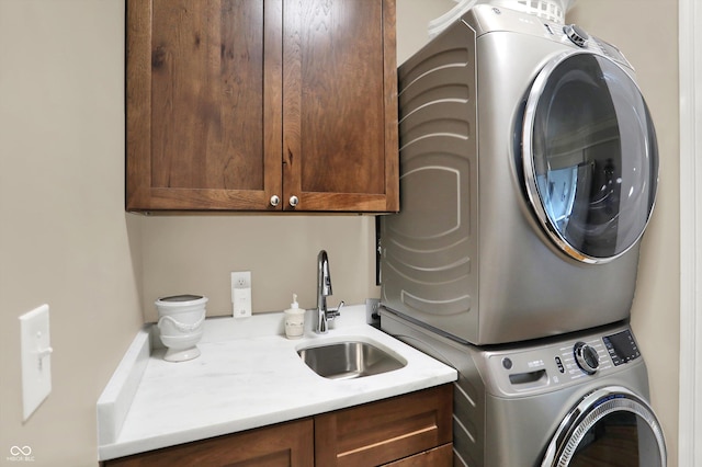 clothes washing area with cabinets, sink, and stacked washer and clothes dryer