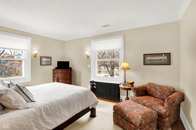 bedroom with light wood-type flooring, radiator heating unit, and crown molding