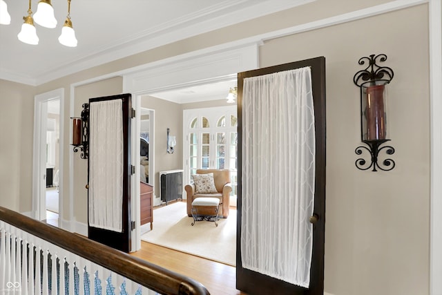 hallway with crown molding, hardwood / wood-style floors, and a chandelier