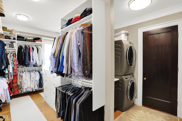 laundry area featuring stacked washer / drying machine, crown molding, and light hardwood / wood-style flooring