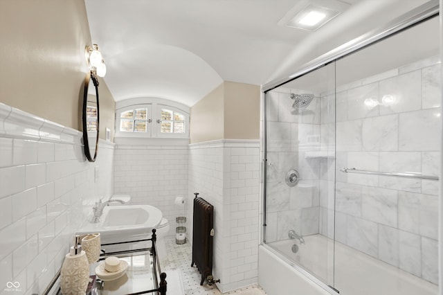 bathroom featuring lofted ceiling, sink, shower / bath combination with glass door, and tile walls