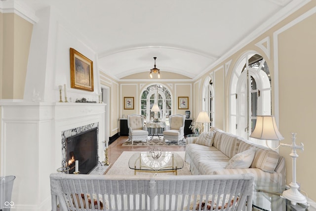 living room featuring a premium fireplace, ornamental molding, and vaulted ceiling