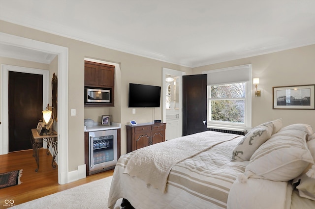 bedroom with light hardwood / wood-style floors, wine cooler, bar, and ornamental molding