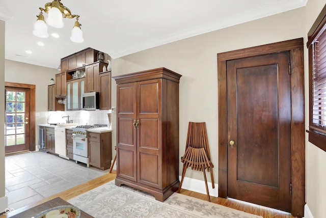 kitchen with tasteful backsplash, white appliances, crown molding, sink, and light hardwood / wood-style floors