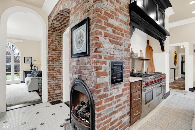 kitchen featuring double oven range, light colored carpet, custom range hood, and ornamental molding