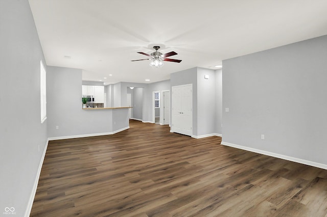 unfurnished living room with dark hardwood / wood-style flooring and ceiling fan