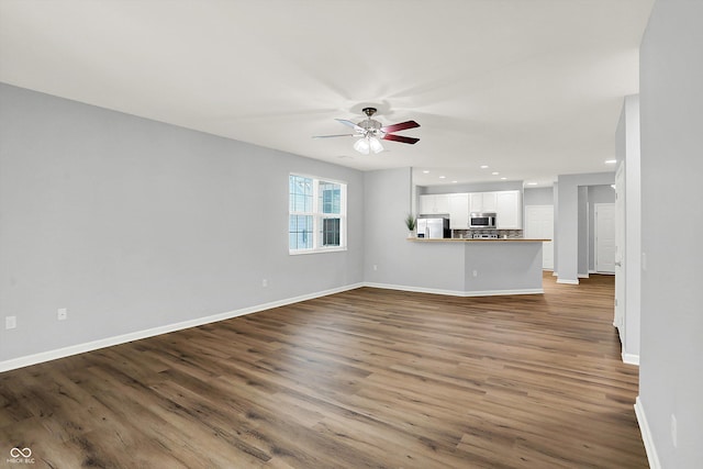 unfurnished living room featuring ceiling fan and dark wood-type flooring