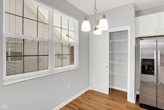 unfurnished dining area featuring light hardwood / wood-style flooring and a notable chandelier