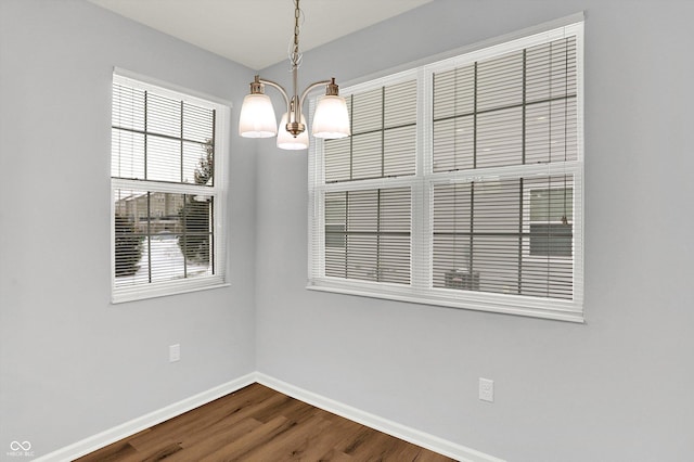 unfurnished dining area featuring wood-type flooring and an inviting chandelier