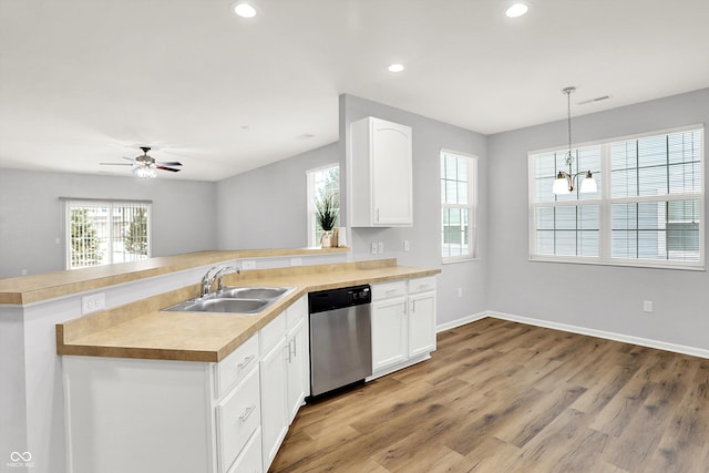 kitchen featuring dishwasher, white cabinets, sink, hanging light fixtures, and kitchen peninsula