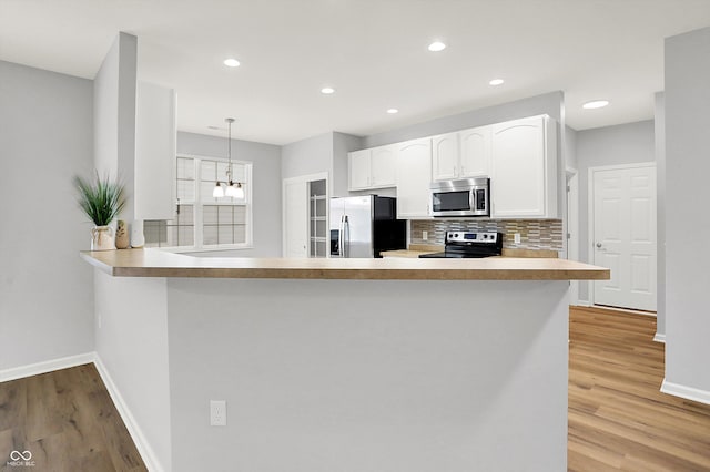 kitchen featuring kitchen peninsula, white cabinetry, pendant lighting, and appliances with stainless steel finishes