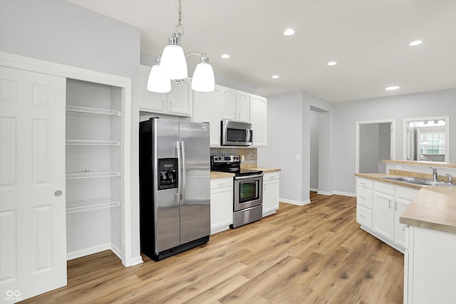 kitchen with decorative light fixtures, white cabinetry, sink, and appliances with stainless steel finishes