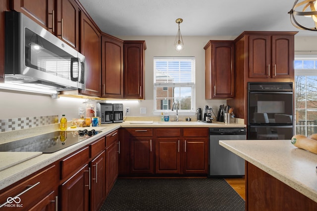 kitchen with light stone countertops, sink, hanging light fixtures, and black appliances