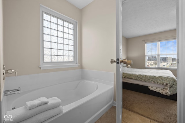 bathroom with tile patterned flooring, a textured ceiling, a bathing tub, and a healthy amount of sunlight