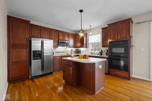 kitchen featuring appliances with stainless steel finishes, a center island, pendant lighting, and wood-type flooring