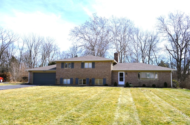 split level home featuring an attached garage, driveway, brick siding, and a front yard