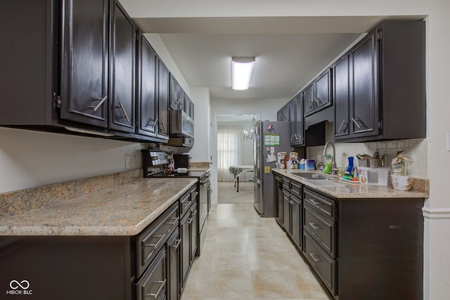 kitchen featuring light stone countertops, appliances with stainless steel finishes, tasteful backsplash, and sink