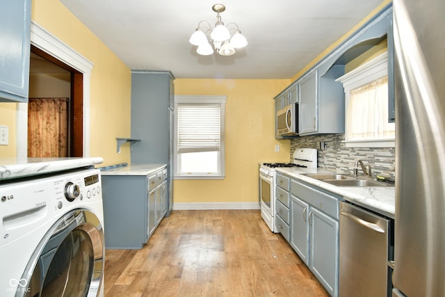 interior space with washer / clothes dryer, sink, light wood-type flooring, and a notable chandelier