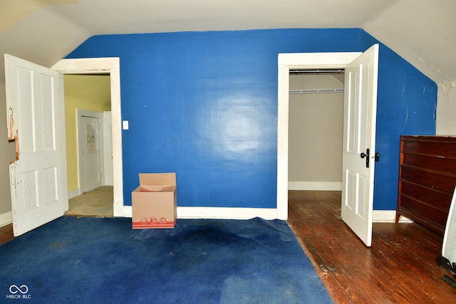 unfurnished bedroom featuring dark hardwood / wood-style floors, lofted ceiling, and a closet