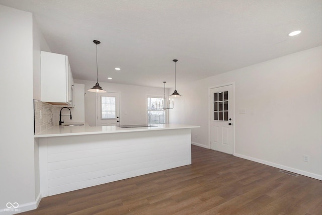 kitchen with white cabinetry, sink, dark wood-type flooring, kitchen peninsula, and decorative light fixtures