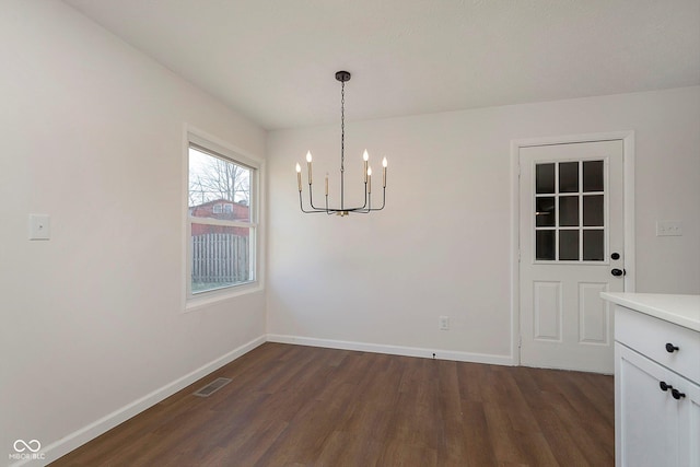 unfurnished dining area featuring dark hardwood / wood-style floors and an inviting chandelier