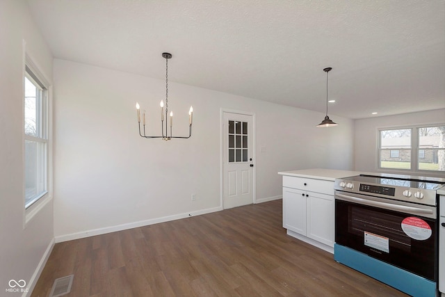 kitchen with a wealth of natural light, dark wood-type flooring, electric stove, pendant lighting, and white cabinets