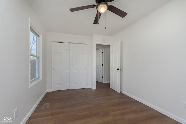 unfurnished bedroom with ceiling fan, dark hardwood / wood-style floors, and a closet