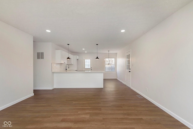 unfurnished living room with a textured ceiling, sink, and dark hardwood / wood-style floors