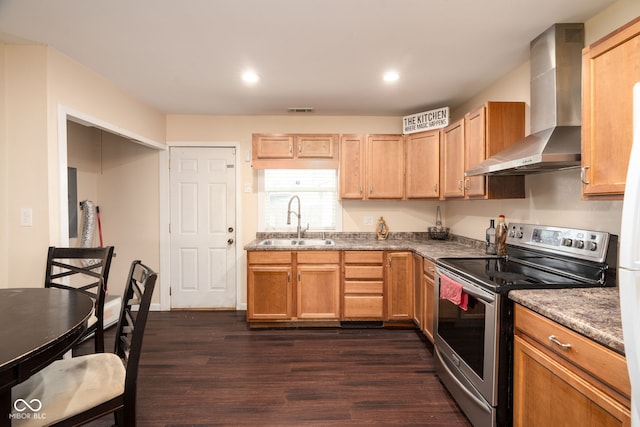 kitchen with stainless steel range with electric cooktop, dark wood-type flooring, sink, wall chimney exhaust hood, and dark stone countertops