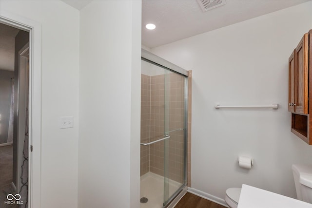 bathroom with hardwood / wood-style floors, toilet, and walk in shower