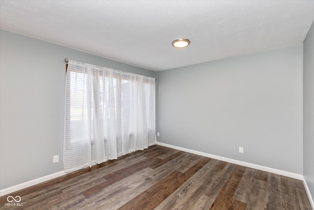 empty room featuring a textured ceiling and dark hardwood / wood-style flooring