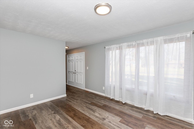 spare room featuring dark hardwood / wood-style flooring and a textured ceiling