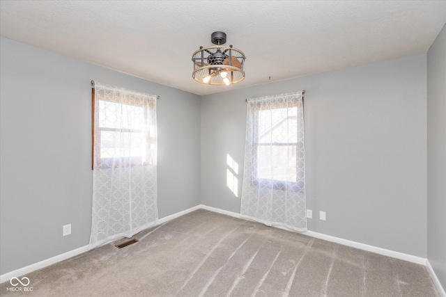 carpeted spare room with a notable chandelier