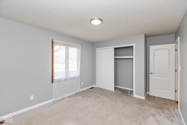 unfurnished bedroom with a closet, light colored carpet, and a textured ceiling