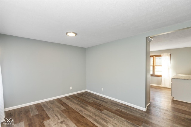 empty room with dark wood-type flooring and a textured ceiling